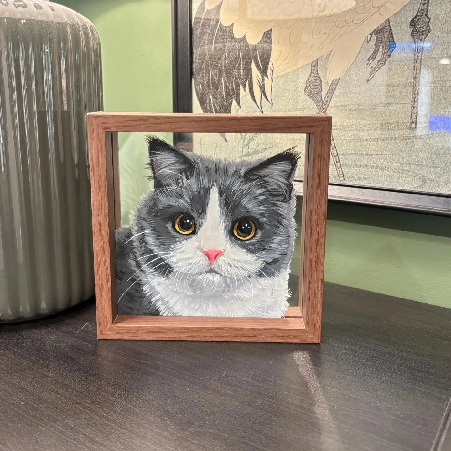 Grey and white cat frame placed beside chair on wood floor.