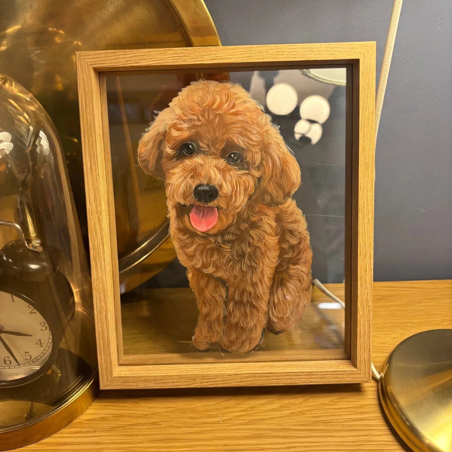 Brown curly dog frame on warmly lit table by small objects.