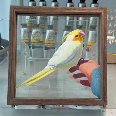 A yellow-and-white cockatiel portrait with the workshop visible through the unpainted glass.